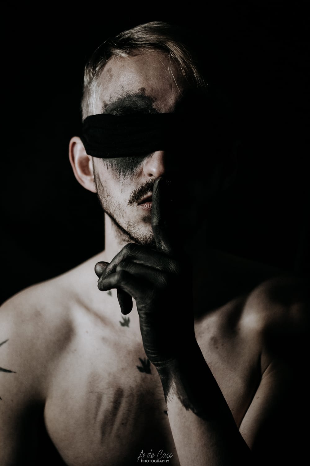 Portrait artistique dark d'un homme torse nu avec des tatouages et les mains noires à Chambéry